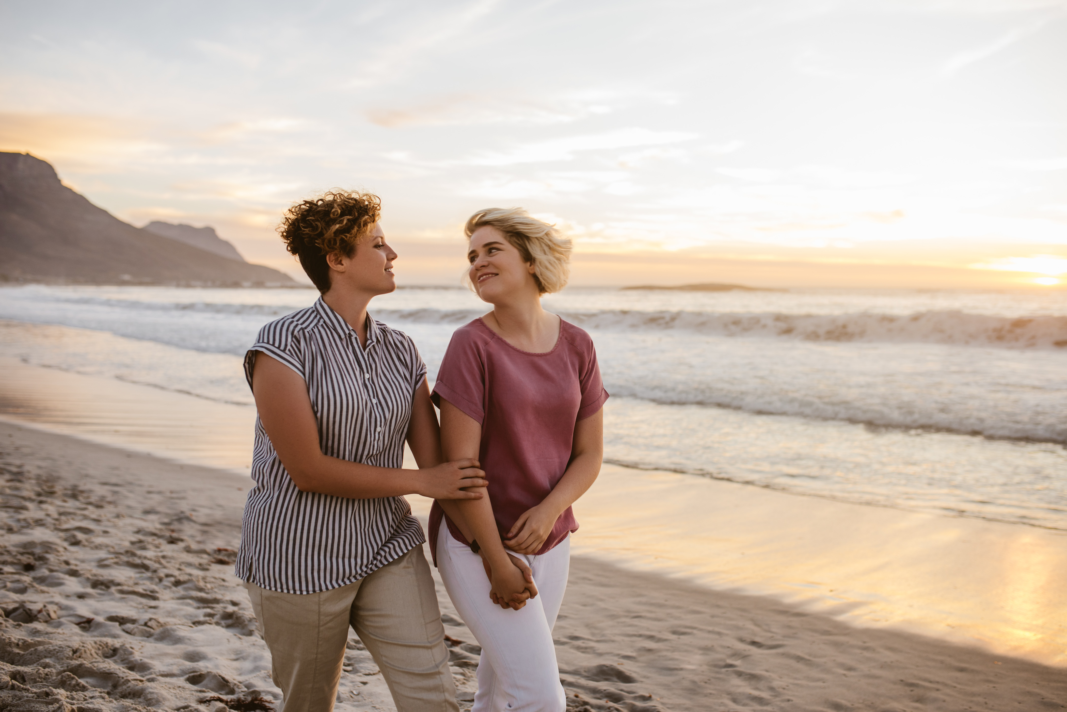 smiling-lesbian-couple-enjoying-a-romantic-walk-along-a-beach_225315319.jpeg